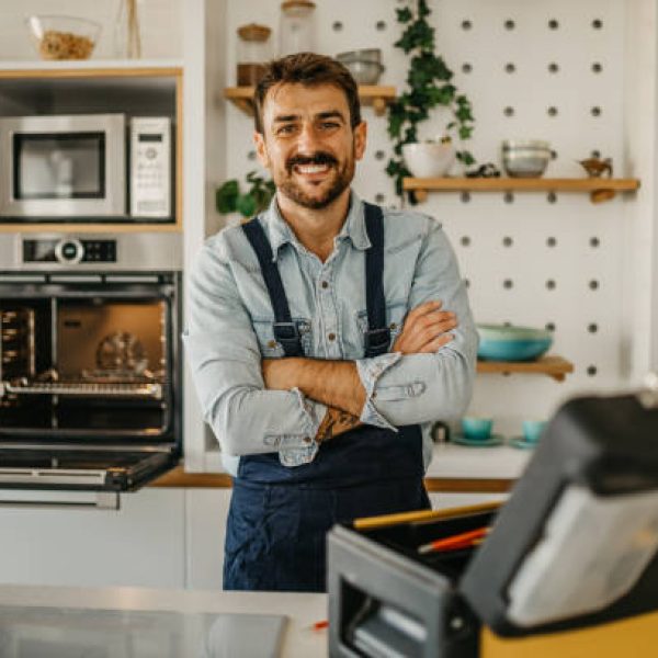 Portrait of a handsome handyman, plumber, or electrician working at a house with his tools and looking at the camera smiling - home improvement concepts